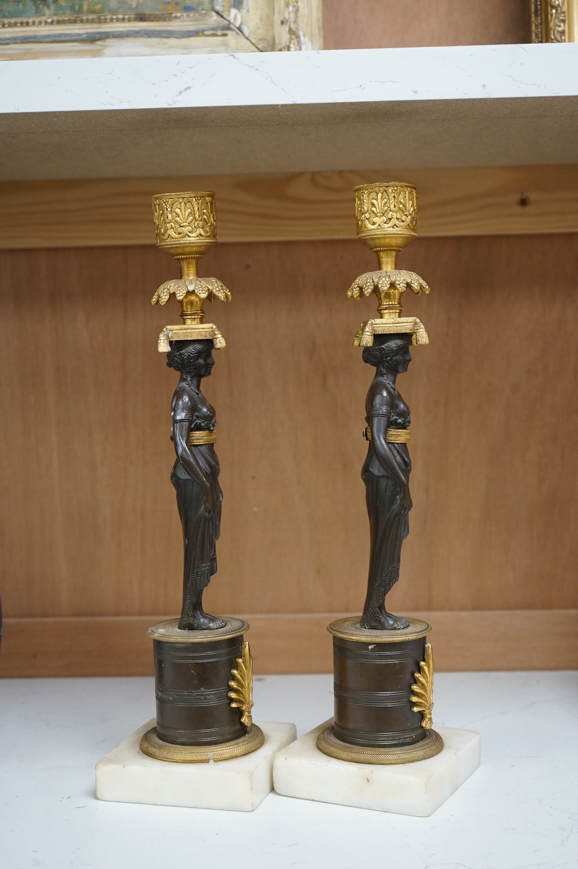 A pair of Regency bronze and gilt candlesticks in the form of standing classical figures mounted on marble bases, 31.5cm high.